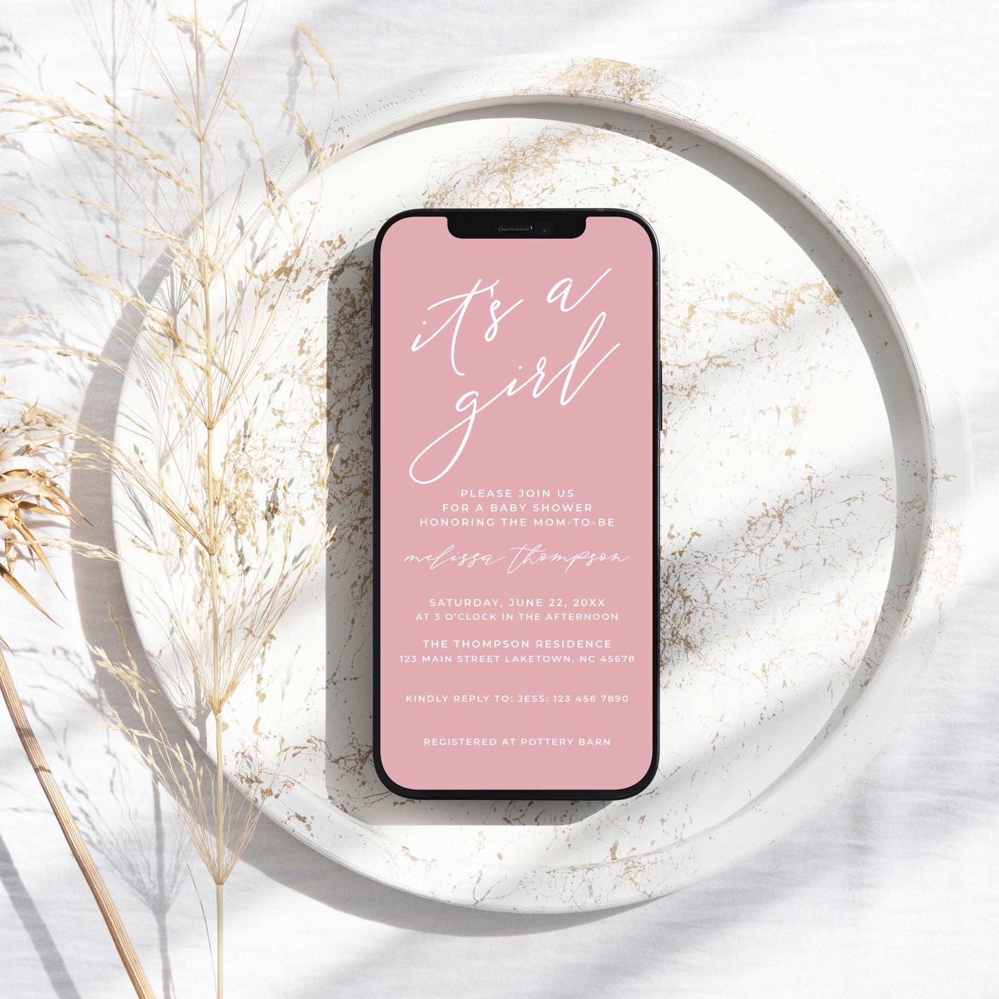 a pink phone on a white plate next to a dried plant