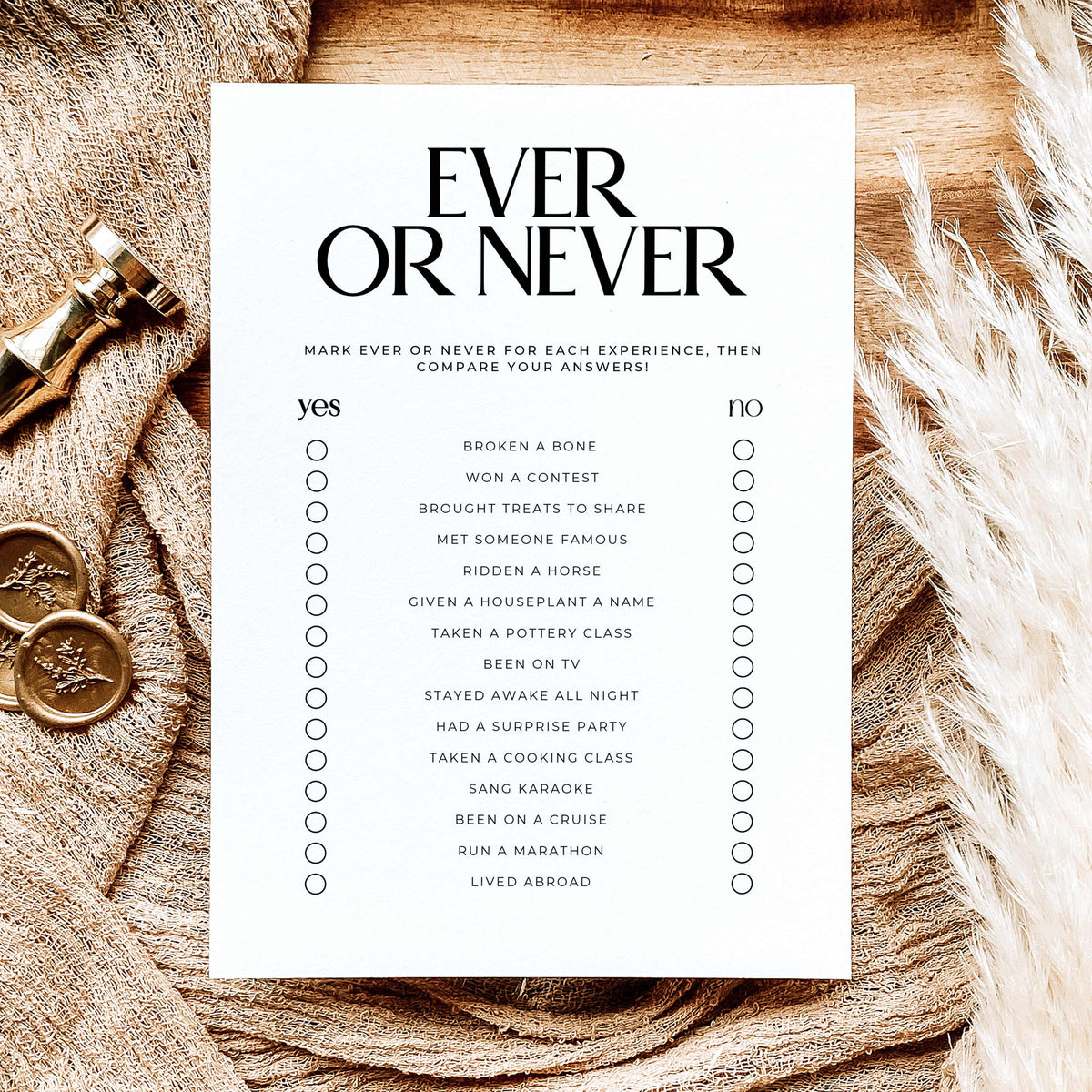 A white printable checklist game titled 'EVER OR NEVER' in bold black text, laid flat on a rustic wood surface. The card lists various experiences under yes and no columns with small circles for marking.