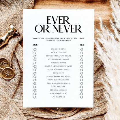 A white printable checklist game titled 'EVER OR NEVER' in bold black text, laid flat on a rustic wood surface. The card lists various experiences under yes and no columns with small circles for marking.