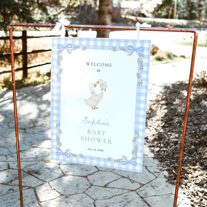 Blue gingham silly goose baby shower welcome sign featuring watercolor mother goose and gosling, pastel blue bows, white daisies, and a delicate floral ribbon border.