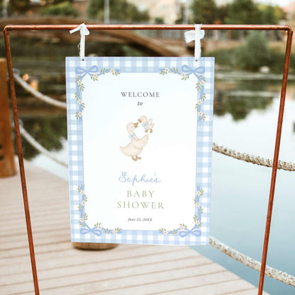 Blue gingham silly goose baby shower welcome sign featuring watercolor mother goose and gosling, pastel blue bows, white daisies, and a delicate floral ribbon border.